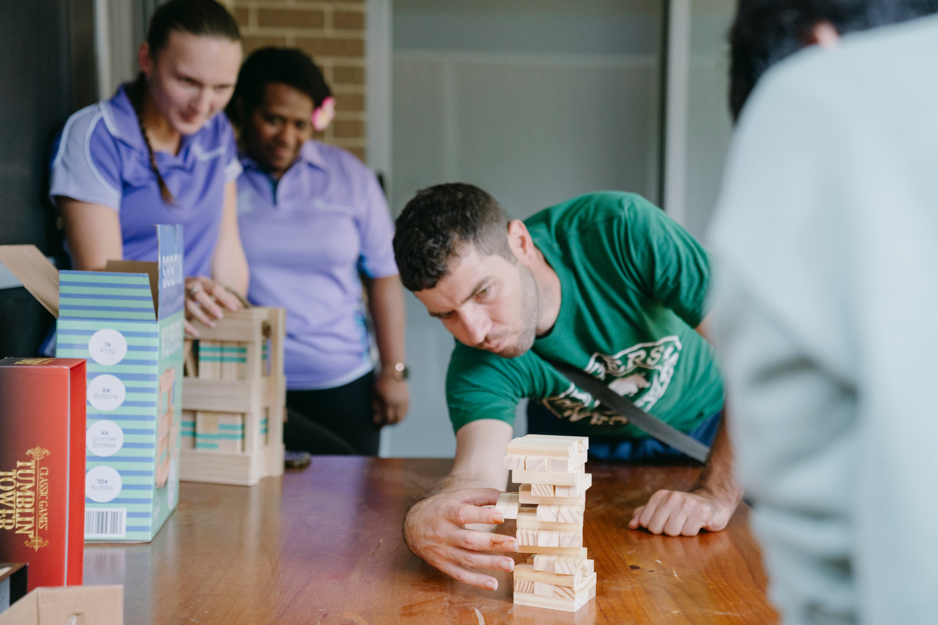 Mark looks concentrated as he is trying to pull a block out of a stack of Jenga blocks without trying to knock it down